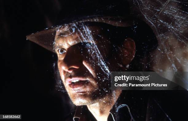 Harrison Ford walks through cobwebs in a scene from the film 'Indiana Jones And The Last Crusade', 1989.