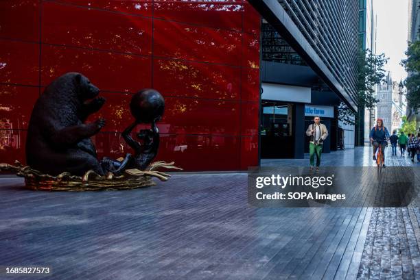 The title of the sculpture is 'The Polar Bear and Dogman wanted everyone to stay cool' as a cyclist and a pedestrian come near to the sculpture with...