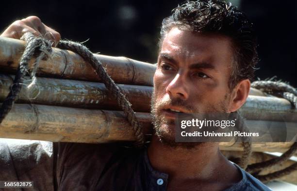 Jean-Claude Van Damme carries bamboo in a scene from the film 'The Quest', 1996.