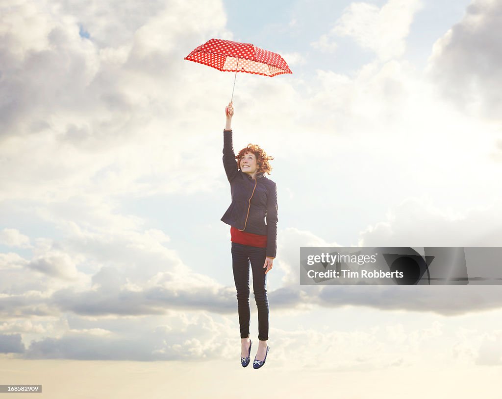 Young woman flying with umbrella.