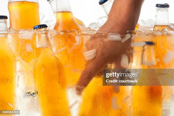 grabbing an ice cold beer from a cooler - beer bottle stockfoto's en -beelden