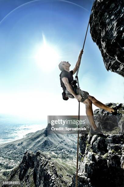 sun flares surround abseiling climber on table mountain - rappelling stock pictures, royalty-free photos & images