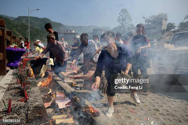 Relatives of earthquake victims burn offerings at the ruins of earthquake-hit Beichuan county during the five year anniversary of the Wenchuan...