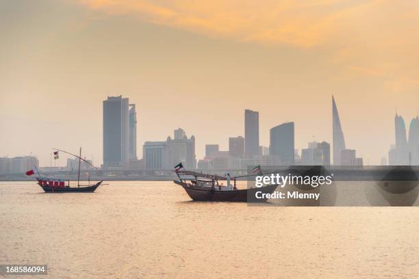 bahrain manama skyline und boote bei sonnenuntergang - bahrein stock-fotos und bilder