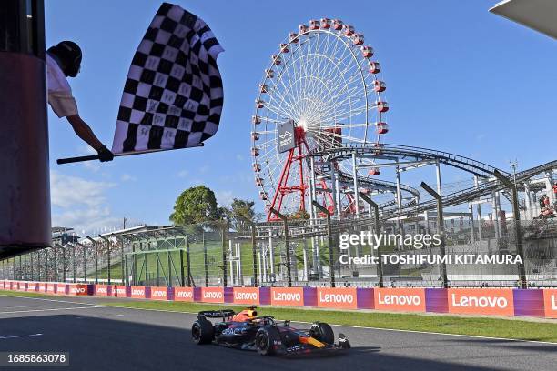 Red Bull Racing's Dutch driver Max Verstappen is greeted by the checkered flag as he wins the Formula One Japanese Grand Prix at the Suzuka circuit,...