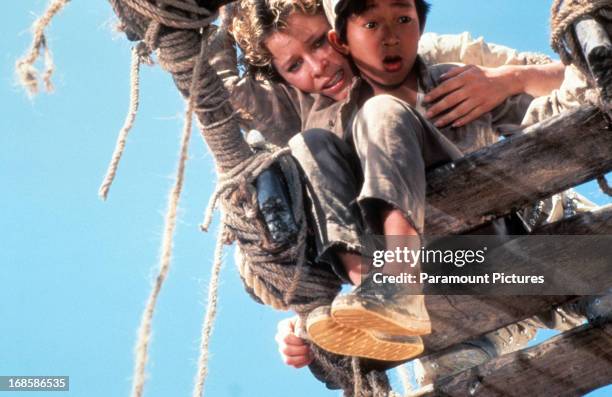 Kate Capshaw holds onto Jonathan Ke Quan over a broken bridge in a scene from the film 'Indiana Jones And The Temple Of Doom', 1984.