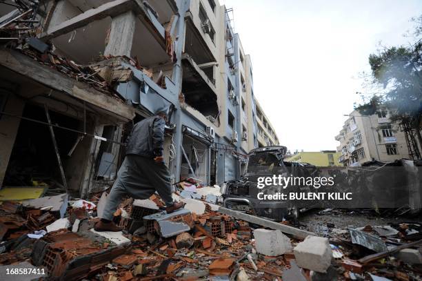 Man walks through the rubble in a street strewn with debris on May 12, 2013 after a car bomb explosion went off on May 11 in Reyhanli in Hatay, just...