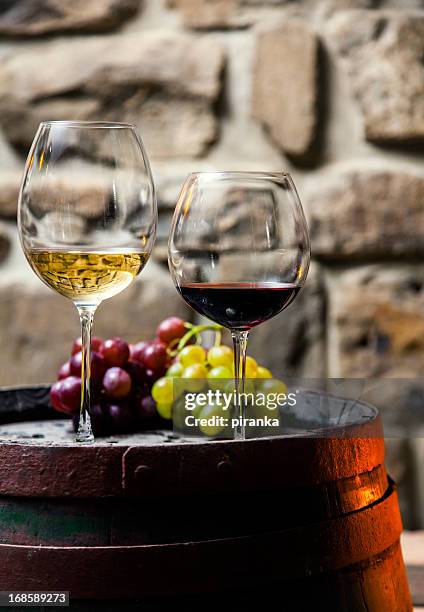 two glasses of red and white wine in the cellar - multi barrel stock pictures, royalty-free photos & images