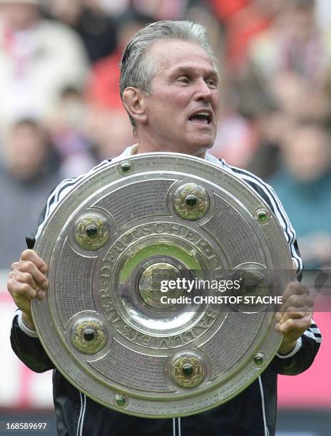 Bayern Munich's head coach Jupp Heynckes holds the German football league champion's trophy while celebrating their champion title, after winning 3:0...
