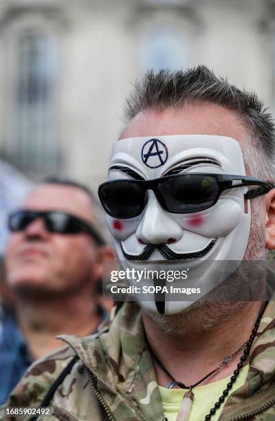 Protester wears an anonymous mask marked with the anarchy symbol as the demonstration cuts through the city. Those who disagree with government...