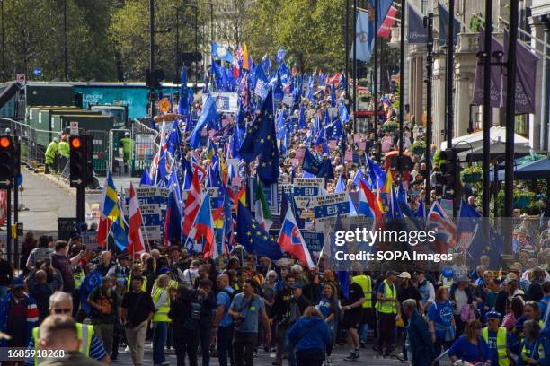 Crowds of protesters holding European Union flags and pro-EU placards pass by Green Park during the demonstration. Thousands of anti-Brexit...