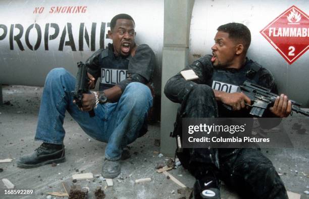 Martin Lawrence and Will Smith yelling at each other while holding machine guns to defend themselves in a scene from the film 'Bad Boys', 1995.