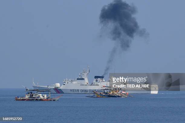 This photo taken on September 20, 2023 shows a Chinese coast guard ship shadowing Philippine fishing boats anchored near the Chinese-controlled...