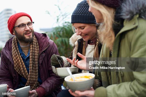 friends eating soup in urban roof garden. - eating soup stock pictures, royalty-free photos & images