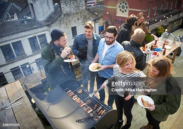 friends in roof garden sharing barbecued food. - grill stock-fotos und bilder