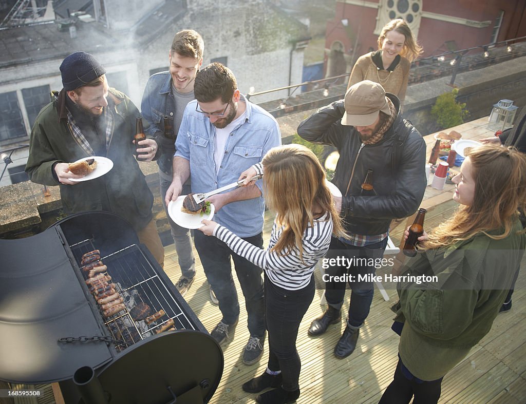 Friends sharing sausages in roof garden.