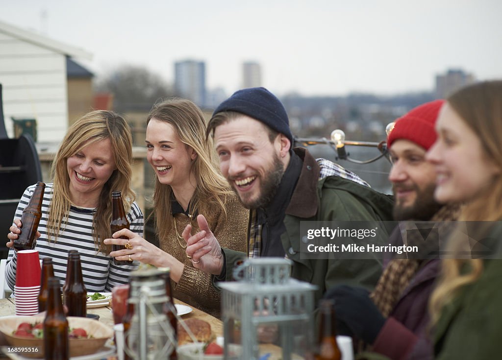 Friends enjoying company at table in roof garden.