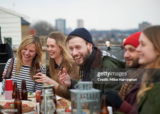 friends enjoying company at table in roof garden. - friends dinner stock pictures, royalty-free photos & images