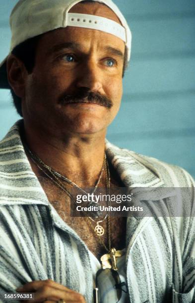Robin Williams wearing a baseball hat backwards and with three necklaces around his neck in a scene from the film 'The Birdcage', 1996.