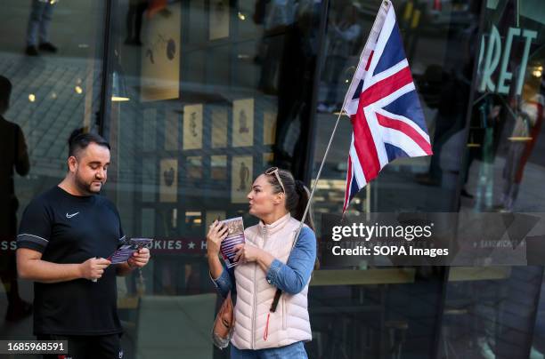 Protester with a union flag speaks to a member of the public and hands out a leaflet. Supporters of Turning Point demonstrate near Bleecker Burger as...