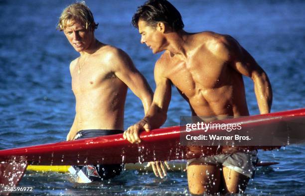 Jan-Michael Vincent and William Katt in the water holding their surfboards in a scene from the film 'Big Wednesday', 1978.