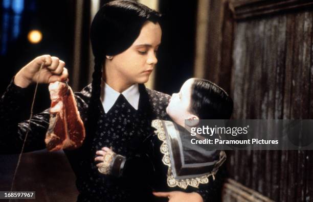 Christina Ricci dangling meat in a scene from the film 'Addams Family Values', 1993.