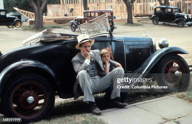 Ryan O'Neal sits with Tatum O'Neal in a scene from the film 'Paper Moon', 1973.