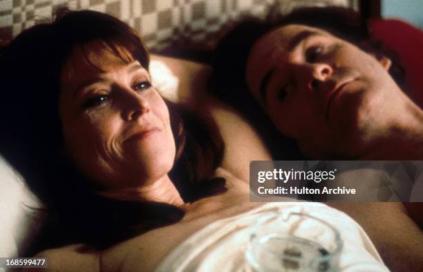 Sigourney Weaver and Kevin Kline laying in bed together in a scene from the film 'The Ice Storm', 1997.