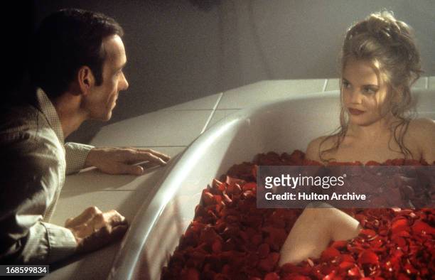 Kevin Spacey looks at Mena Suvari as she bathes in rose pedals in a scene from the film 'American Beauty', 1999.