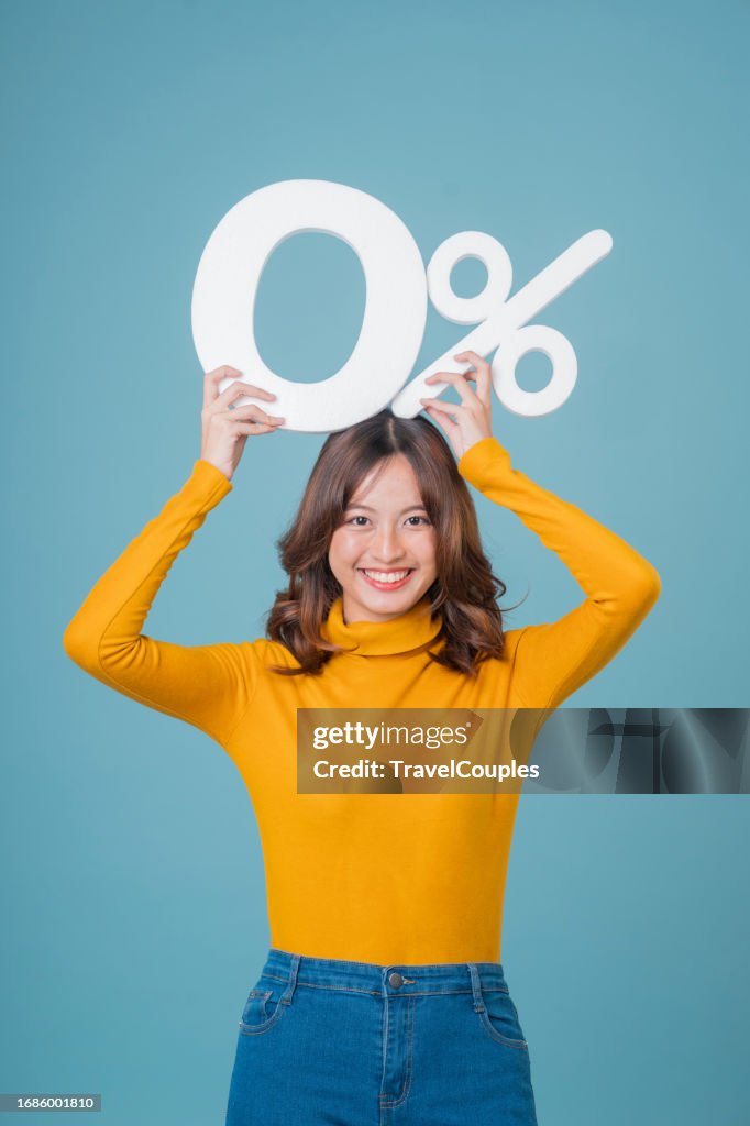 Asian business woman standing and holding 0% number or zero percent isolated over light blue background.