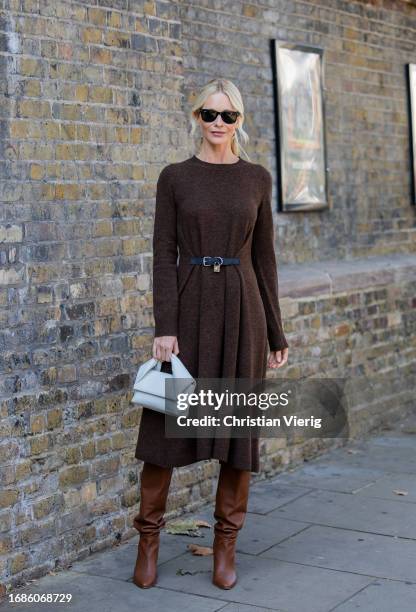 Poppy Delevingne wears brown belted dress with long sleeves, grey bag, brown boots outside JW Anderson during London Fashion Week September 2023 at...