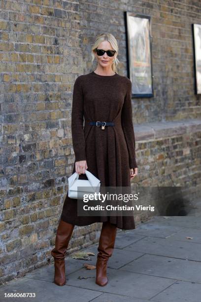 Poppy Delevingne wears brown belted dress with long sleeves, grey bag, brown boots outside JW Anderson during London Fashion Week September 2023 at...