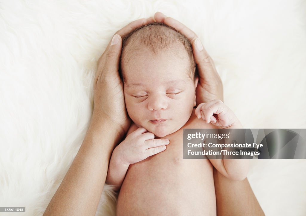 Mother holding sleeping baby with hands