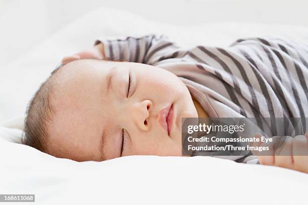 close up of baby sleeping on bed - sólo bebés fotografías e imágenes de stock