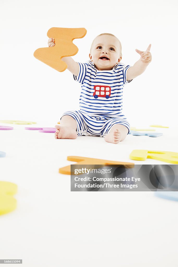 Smiling baby playing with toy letters