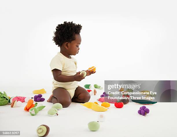 baby playing with toy fruit - compassionate eye foundation stock-fotos und bilder