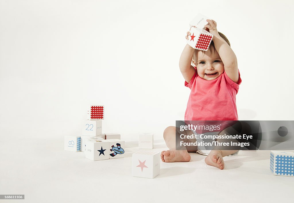 Smiling baby playing with wooden blocks