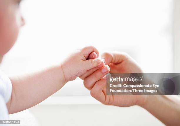 baby holding mother's finger - hand child stock pictures, royalty-free photos & images