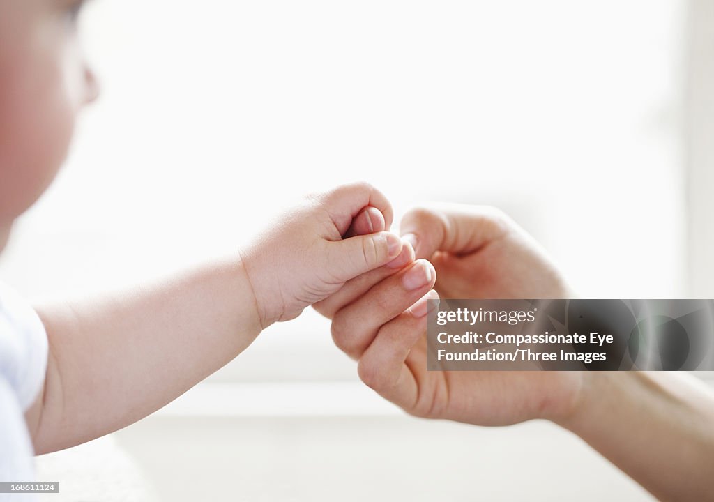 Baby holding mother's finger