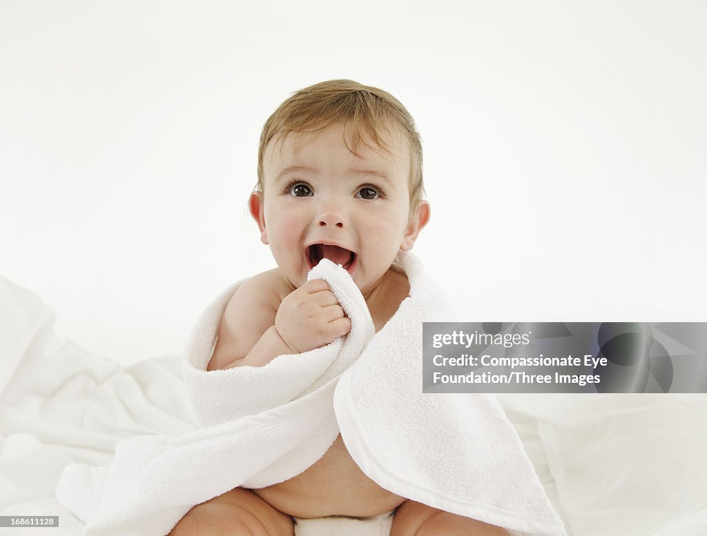 Smiling baby wrapped in towel