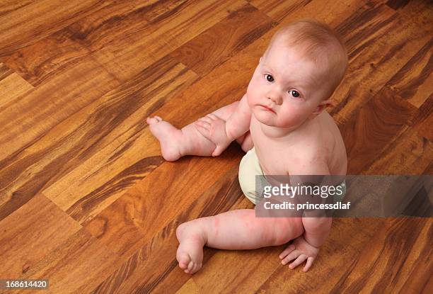 unhappy baby with a rash sits on a wooden floor - reusable diaper stock pictures, royalty-free photos & images