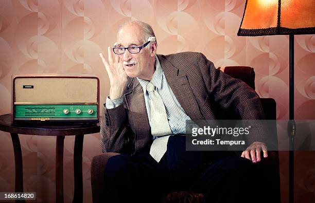 senior man leaning in to listen to retro radio - radio stockfoto's en -beelden