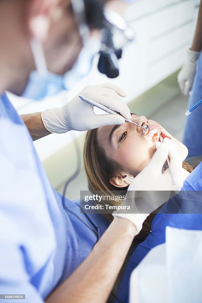 Dentist inspecting female patient's teeth