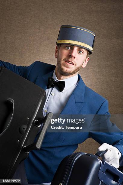bell boy in trouble with heavy luggage _ vertical - door attendant stock pictures, royalty-free photos & images