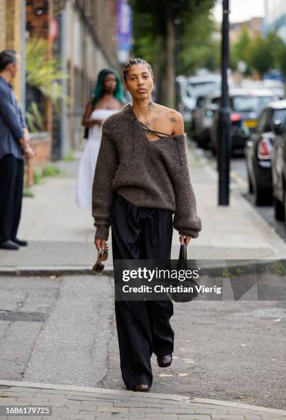 Guest wears brown knit, black bag, pants outside 16Arlington during London Fashion Week September 2023 at the on September 16, 2023 in London,...