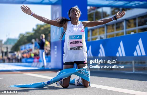 September 2023, Berlin: Athletics: Berlin Marathon. Tigst Assefa from Ethiopia kneels on the ground after her success at the BMW Berlin Marathon....