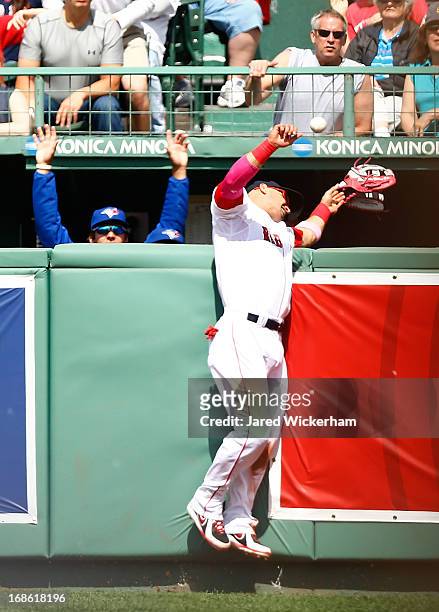Shane Victorino of the Boston Red Sox hits the wall and loses his glove as the ball hit by Emilio Bonifacio of the Toronto Blue Jays goes over the...