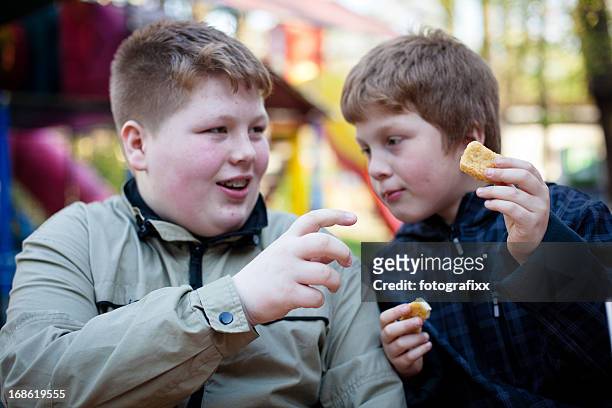 unhealthy eating: two overweight boys eating chicken nuggets - chubby teen boy stock pictures, royalty-free photos & images