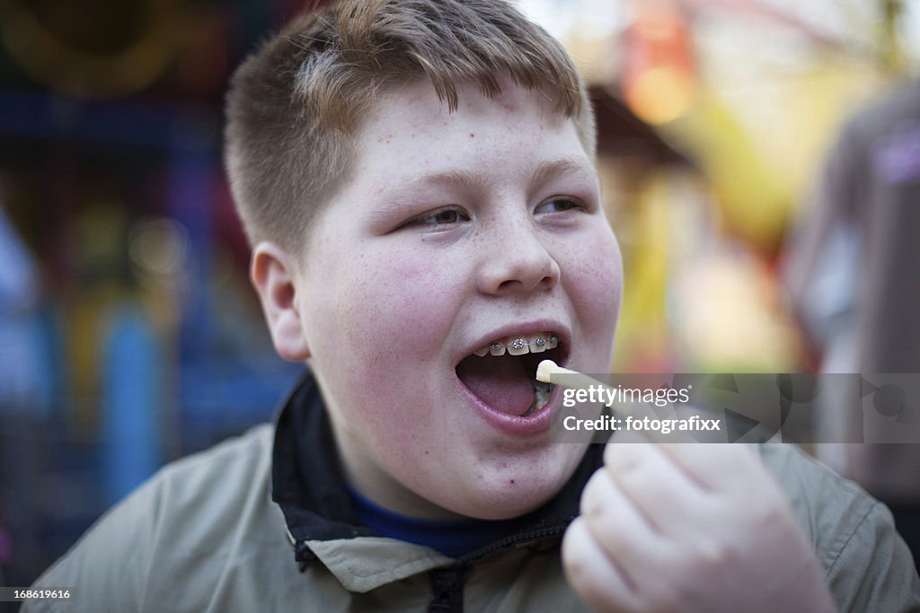 Unhealthy Eating: redhead overweight teenage boy eats french fries