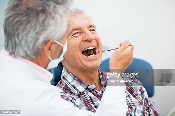 hombre mayor en el dentista - mouth fotografías e imágenes de stock